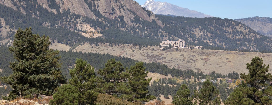 The National Center for Atmospheric Research sits nestled in the Rocky Mountain foothills with a snow dusted Longs Peak and the Boulder flatirons in the background.