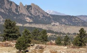 The National Center for Atmospheric Research sits nestled in the Rocky Mountain foothills with a snow dusted Longs Peak and the Boulder flatirons in the background.